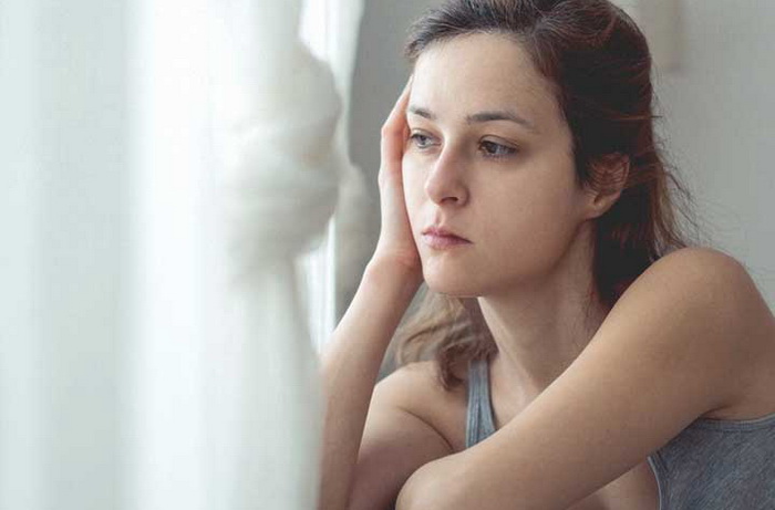 Молодая девушка у окна грустит